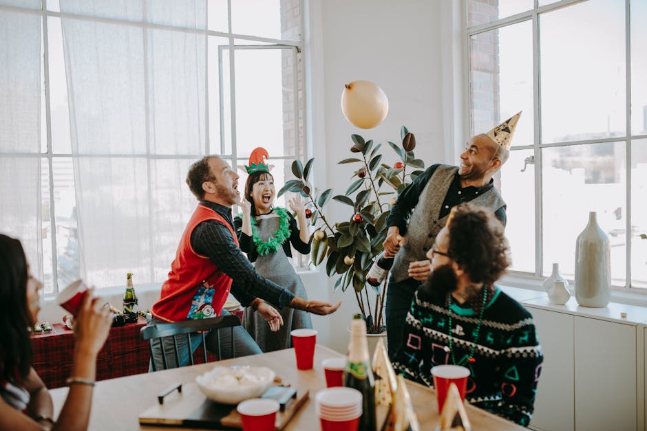 Cheerful office holiday party with adults in festive Christmas sweaters celebrating with food and drinks.